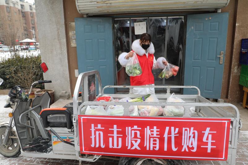 A volunteer helps residents who are affected by the measures to prevent and control the novel coronavirus to purchase daily necessities from a store in Tangshan, Hebei province, China.  Reuters