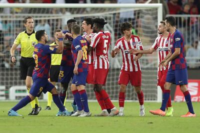 Barcelona's Luis Suarez, left, fights with Atletico Madrid's Stefan Savic, center, during the Spanish Super Cup semifinal soccer match between Barcelona and Atletico Madrid at King Abdullah stadium in Jiddah, Saudi Arabia, Thursday, Jan. 9, 2020. (AP Photo/Hassan Ammar)