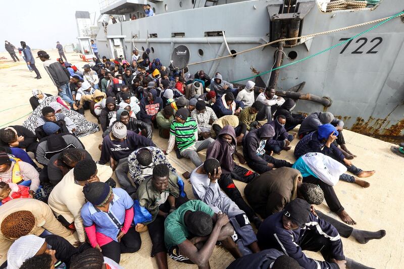 African migrants rescued from a ship off the coast of Zawiyah, about 45 kilometres west of the Libyan capital Tripoli, sit at the dock at the capital's naval base on March 10, 2018. (Photo by MAHMUD TURKIA / AFP)