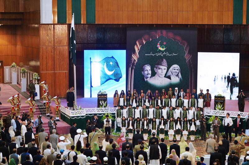 Pakistan's President Mamnoon Hussain (top L) stands under Pakistan's national flag while listening the national anthem along with others during a ceremony to mark the country's Independence Day in Islamabad on August 14, 2017.
Pakistan’s Independence Day, which is annually held on August 14, celebrates the country’s independence from the British rule on that date in 1947. / AFP PHOTO / AAMIR QURESHI
