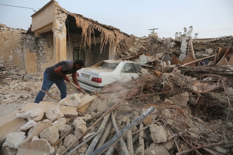 A villager in Sayeh Khosh clears rubble after a powerful earthquake struck southern Iran early on Saturday. AP