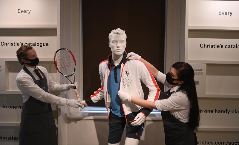 Christie's employees pose for photographers next to a mannequin wearing an outfit and racket used by Swiss tennis player Roger Federer during the 2009 French Open at the Christie's auction house, in London.