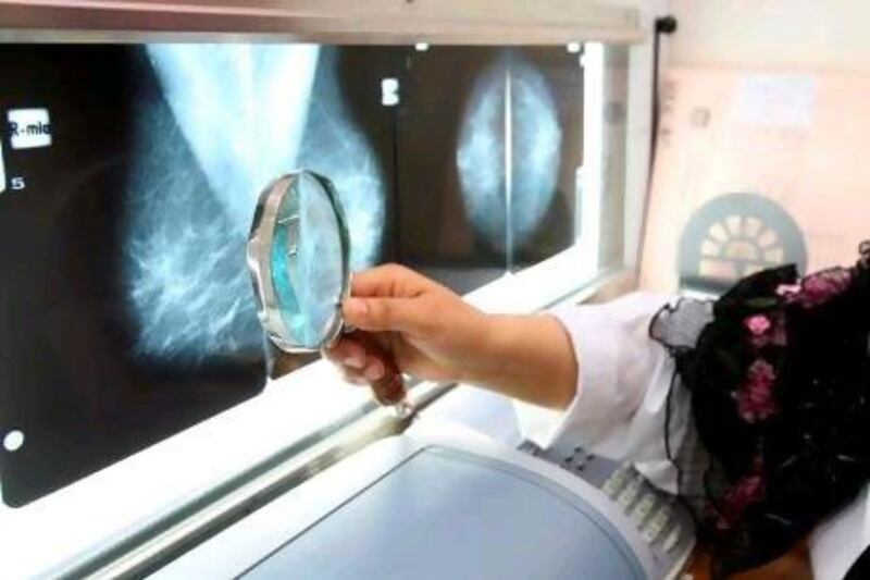 Dr. Jalaa Taher looks at chest x-rays at the National Health Screening Program for Women and Children, part of the Ministry of Health. She and several other doctors are part of a global initiative to promote breast cancer awareness.