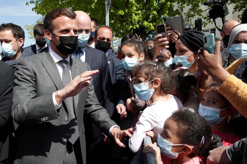 French President Emmanuel Macron (C) greets people after his visit of a school of Melun, south of Paris, on April 26, 2021. Nursery and primary schools reopened on April 26, 2021 across France after a three-week closure in the first step out of the country's partial lockdown. Meanwhile, high schools students are following online classes. / AFP / POOL / Thibault Camus
