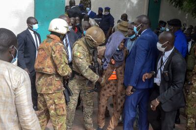 Security personnel escort an alleged attacker from the Grand Mosque in Bamako after two assailants attempted to stab Mali's interim president, Col Assimi Goita.