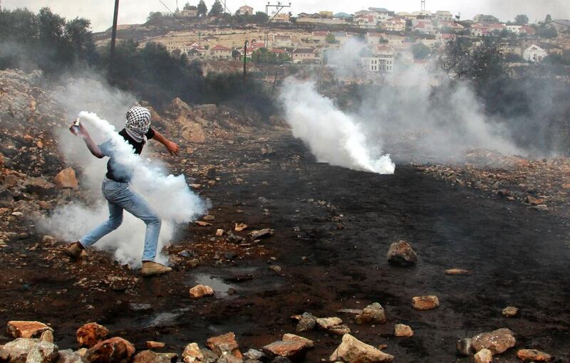 A Palestinian protester throws back an Israeli tear-gas canister following a demonstration against the expropriation of Palestinian land by Israel on Friday in the village of Kfar Qaddum in the West Bank. Jaafar Ashtiyeh / AFP