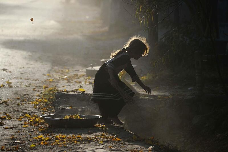 An Afghan girl collects fallen autumn leaves in Jalalabad. Poverty and an continuing insurgency by the ousted Taliban still pose a threat to the stability of the country. Noorullah Shirzada / AFP