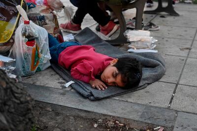 TOPSHOT - A child rests by her family's belongings as Afghan families who arrived from Moria camp on the island of Lesbos, camp at a central Athens square on June 14, 2020 after receiving a blue stamp which allowed them to travel to the mainland. At least 66 refugees, who arrived from the island after their asylum applications where approved, camp on the square as they have no place to stay in Athens.  / AFP / Louisa GOULIAMAKI
