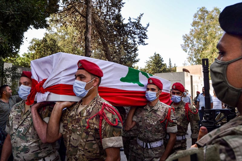 Lebanese army soldiers, clad in masks due to the COVID-19 coronavirus pandemic, carry the flag-draped coffin of their fallen comrade who was killed in an overnight shooting, in Lebanon's northern city of Tripoli on September 27, 2020. Two army soldiers were killed by "terrorists" overnight in northern Lebanon, the army said. "Terrorists in a car opened fire on the guards of an army post in the locality of Arman-Minyeh... Two soldiers were killed, in addition to one terrorist," the army said in a statement. The incident comes amid an ongoing operation to locate a cell involved in the recent killing of four soldiers and three other people. / AFP / Fathi AL-MASRI
