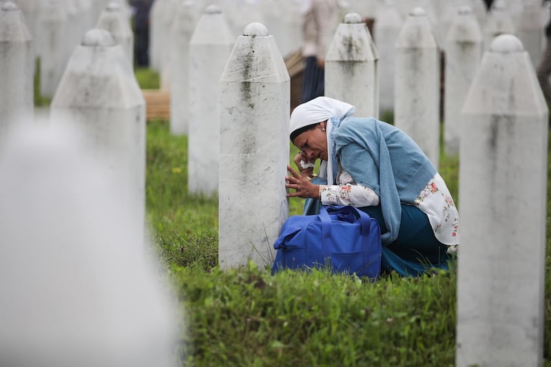A woman mourns by a gravestone on the Potocari Memorial Center in Srebrenica, Bosnia and Herzegovina, July 11, 2018. EPA