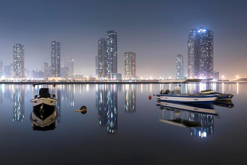SHARJAH, UNITED ARAB EMIRATES. 30 September 2017. STANDALONE. The Sharjah skyline lights reflect in the Al Khan Lagoon while moored vessels wait out the humid night. (Photo: Antonie Robertson/The National) Journalist: None. Section: Standalone.