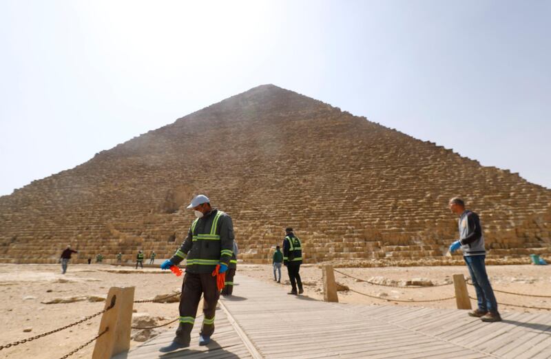 Egyptian municipality workers disinfect the Giza pyramids necropolis on the southwestern outskirts of the Egyptian capital Cairo on March 25, 2020 as protective a measure against the spread of the coronavirus COVID-19.  / AFP / Khaled DESOUKI

