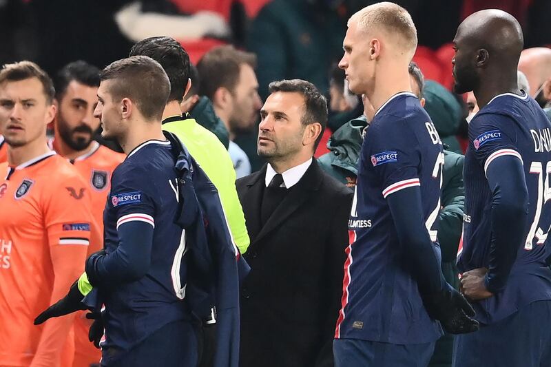 Istanbul Basaksehir coach Okan Buruk (C) looks on as he leaves the pitch after the game was suspended amid allegations of racism by one of the match officials. AFP