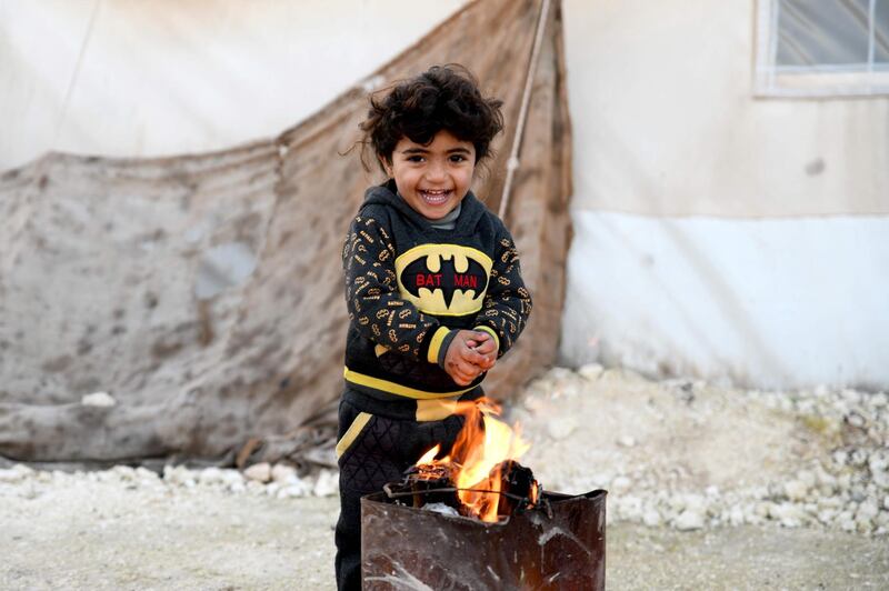 A displaced Syrian child poses for a photograph in a flooded camp near Dayr Ballut, Aleppo province. AFP