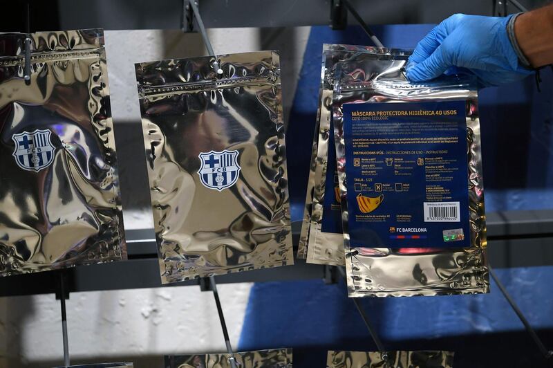 An employee places a mask bearing the logo of FC Barcelona on a shelf at the FC Barcelona store. AFP