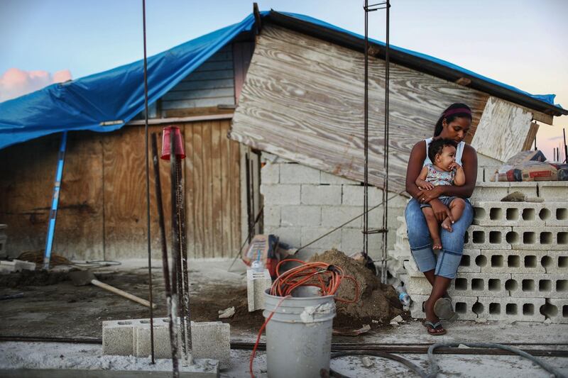SAN ISIDRO, PUERTO RICO - DECEMBER 23:  Mother Isamar holds her baby Saniel, 9 months, at their makeshift home, under reconstruction, after being mostly destroyed by Hurricane Maria, on December 23, 2017 in San Isidro, Puerto Rico. Their neighborhood remains without electricity. Barely three months after Hurricane Maria made landfall, approximately one-third of the devastated island is still without electricity. While the official death toll from the massive storm remains at 64, The New York Times recently reported the actual toll for the storm and its aftermath likely stands at more than 1,000. A recount was ordered by the governor as the holiday season approached.  (Photo by Mario Tama/Getty Images) *** BESTPIX ***