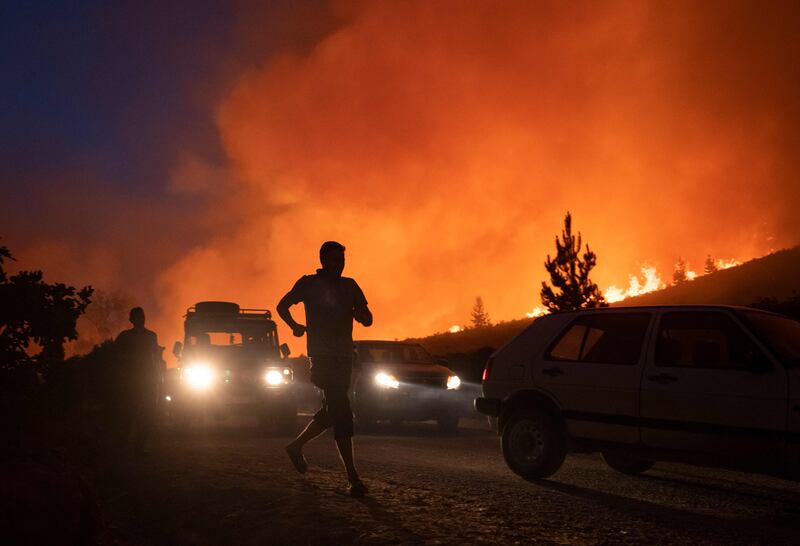 People run away as smoke billows from fires that destroyed some 200 hectares of forest in Chefchaouen, northern Morocco.