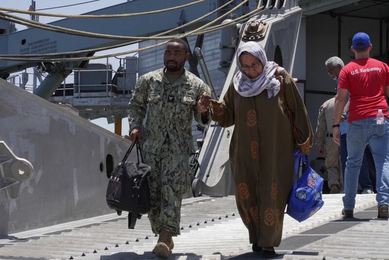 An US Navy serviceman helps a woman disembark from the USNS Brunswick after its arrival in Jeddah, Saudi Arabia. Reuters