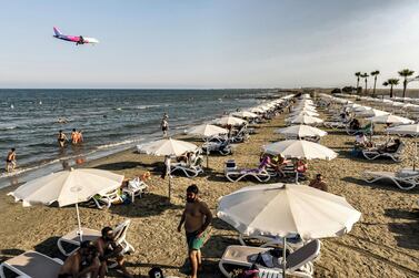 A plane on its descent to Cyprus's Larnaca International Airport flies over beachgoers at a nearby beach along the Mediterranean. AFP