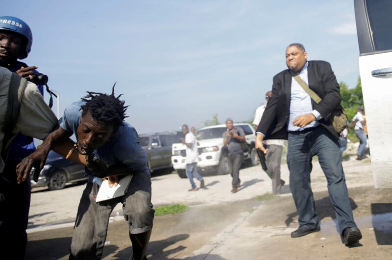 People run as Haiti's Senator Jean Marie Ralph Fethiere holds a gun in Port-au-Prince, Haiti.  Reuters