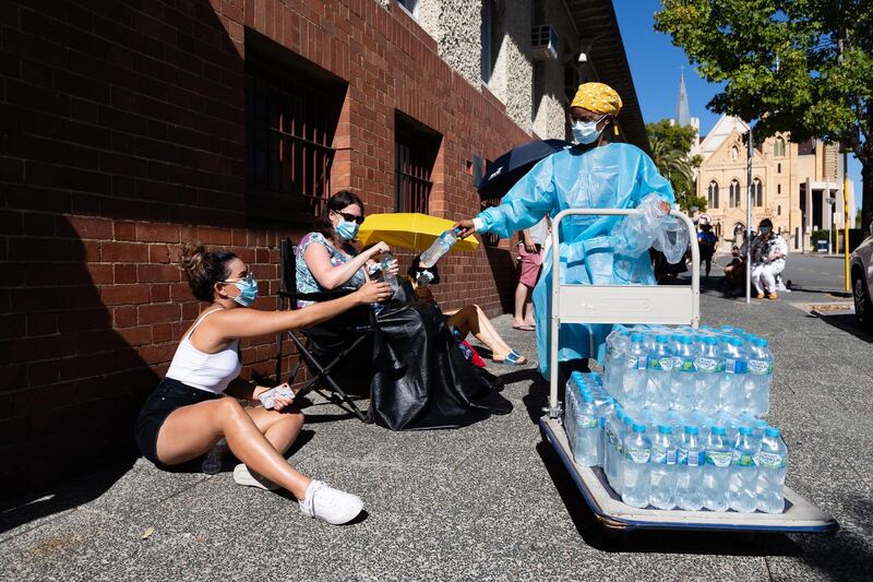 Medical staff hand out water to the long lines of people waiting to be tested for Covid-19 at the Covid Clinic in Royal Perth Hospital in Perth, Australia. EPA