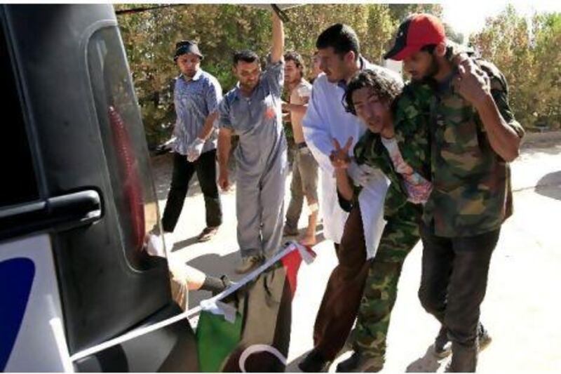 A Libyan rebel fighter and volunteers help a fighter injured during a battle with forces loyal to Muammar Qaddafi near Misurata yesterday. Zohra Bensemra / Reuters