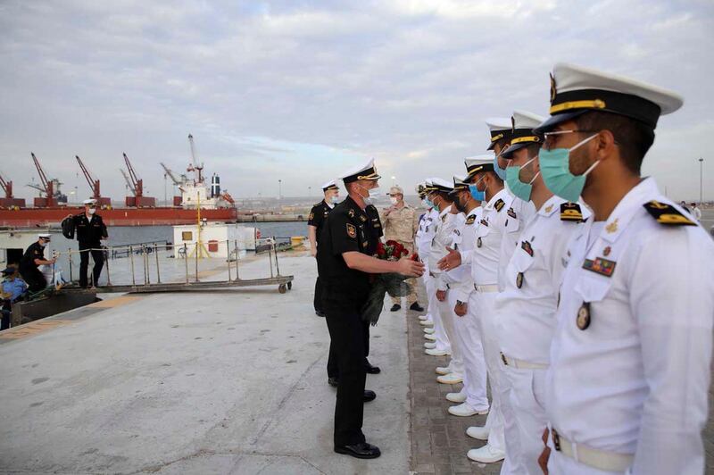 In this photo released Tuesday, Feb. 16, 2021, by the Iranian army, Russian commander, in black uniforms, are welcomed by a group of Iranian navy members as they arrive for a joint naval exercise with the Iranian navy and Iran's Revolutionary Guard navy. Iranian and Russian militaries have kicked off a joint naval drill in the Indian Ocean aimed at boosting security of maritime trade in the region, Iran's state TV reported on Tuesday. (Iranian Army via AP)