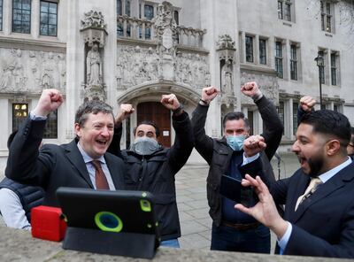 Uber drivers of the (ADCU), App Drivers & Couriers Union, celebrate as they listen to the court decision on a tablet computer outside the Supreme Court in London, Friday, Feb. 19, 2021.  The U.K. Supreme Court ruled Friday that Uber drivers should be classed as â€œworkersâ€ and not self employed.(AP Photo/Frank Augstein)