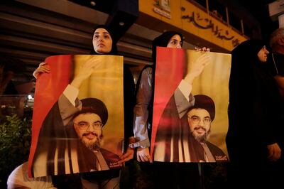 FILE - In this Oct. 25, 2019 file photo, supporters of Hezbollah leader Sayyed Hassan Nasrallah hold his picture, in the southern suburbs of Beirut, Lebanon. Nasrallah has thrown his support behind the Lebanese government seeking financial assistance from the International Monetary Fund but said it should negotiate the conditions cautiously. Nasrallahâ€™s comments on Monday, May 4, 2020, came four days after the countryâ€™s prime minister said Lebanon will seek a rescue deal from the IMF to help the nation find a way out of a crippling financial crisis. (AP Photo/Hassan Ammar, File)