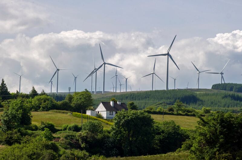 Wind turbines loom over a house in Arigna, Ireland. The world's need for a large-scale energy transition is crucial – and needs to be funded. Getty