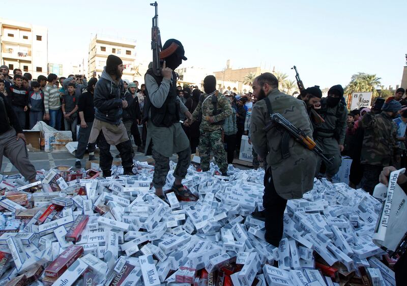 ISIS fighters stand on confiscated cigarettes before setting them on fire in Raqqa in April 2014.