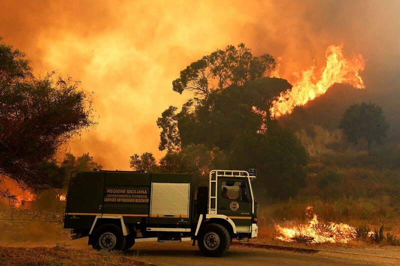 (FILES) This file photo taken on July 10, 2017 shows a fire rescue vehicle in the Annunziata district of Messina, northeastern Sicily, as a fire rages.
Fifteen firefighters have been arrested in Sicily on suspicion of having started fires in order to receive bonus payments, police on the Italian island said on August 7, 2017. / AFP PHOTO / GIOVANNI ISOLINO