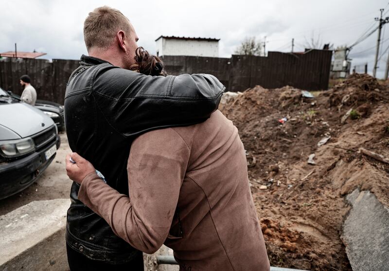 A mother waits for police officers to exhume the body of her son from a well at a fuel station in Buzova, Kyiv region. According to the head of the village, he was killed by Russian soldiers.  Reuters