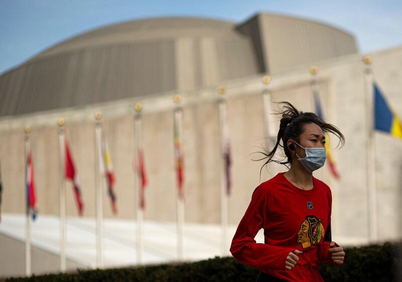 (FILES) In this file photo a woman wearing a facemask runs past the United Nations headquarters in New York on March 11, 2021, one year after the pandemic was officially declared.  Americans vaccinated against the coronavirus will no longer need to wear masks outdoors, except at crowded events, US government health authorities said April 27, 2021. Under the newly released guidance from the Centers for Disease Control, fully vaccinated people can eat, walk or attend small gatherings outside without a mask. Masks are still considered necessary for vaccinated people if they are at concerts, parades or large sporting events, even when outdoors, the CDC said.
 / AFP / Kena Betancur
