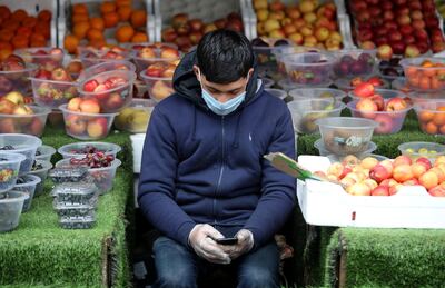  A man wearing a protective face mask and gloves looks at his phone whilst waiting for customers at a shop in Birmingham as the spread of the coronavirus disease (COVID-19) continues, Birmingham, Britain, March 30, 2020. REUTERS/Carl Recine