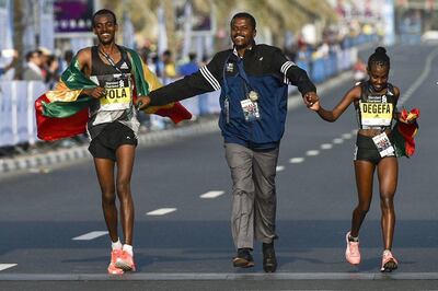 Ethiopian runners Worknesh Degefa, right, and Tamirat Tola, left, celebrate after winning the Dubai marathon in 2017 with middle-distance legend Kenenisa Bekele. AFP