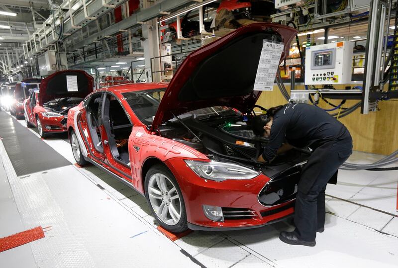 FILE - In this May 14, 2015, file photo, Tesla employees work on a Model S cars in the Tesla factory in Fremont, Calif. Tesla CEO Elon Musk is threatening to pull the company's factory and headquarters out of California in a spat with local officials over reopening an electric vehicle plant. On Twitter Saturday afternoon, May 9, 2020, Musk threatened to sue over health department coronavirus restrictions that have stopped Tesla from restarting production at its factory in Fremont south of San Francisco. (AP Photo/Jeff Chiu, File)