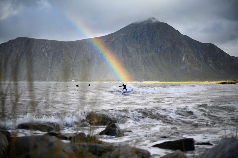 Surfer Anker Olsen Frantzen rides a wave under a rainbow during a free surf session in Flakstad, Norway. Olivier Morin/AFP