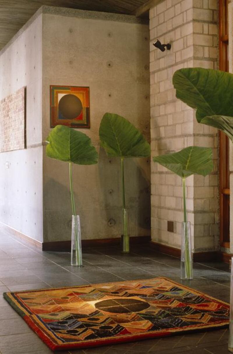 Palm leaves in glass vases set on tiled floor in modern hallway.