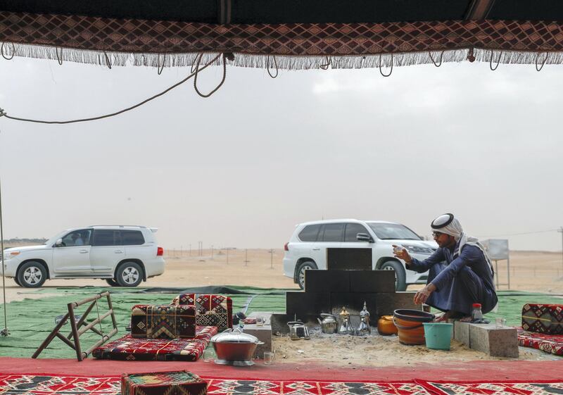 Abu Dhabi, United Arab Emirates, December 11,2019.  
  -- Hamad Al Merri warms himself by the fireside at his family's tent in the dunes of Al Dhafra.
Victor Besa/The National
Section:  NA
Reporter:  Anna Zacharias