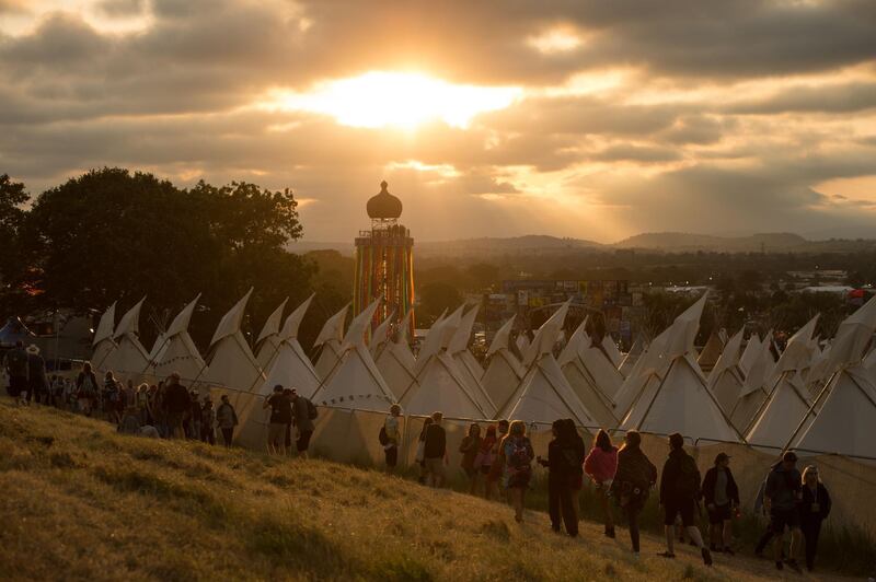 (FILES) In this file photo taken on June 26, 2019 The sun sets as revellers look out from a viewing platform over the Tipi Village as they attend the Glastonbury Festival of Music and Performing Arts on Worthy Farm near the village of Pilton in Somerset, South West England. The organisers of Britain's Glastonbury Festival announced on January 21, 2021 they had been forced to cancel the music event for the second year in a row because of the coronavirus pandemic. / AFP / OLI SCARFF
