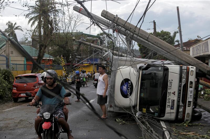 Residents stand among the destruction after Typhoon Kammuri hit Camalig town, Philippines. Reuters