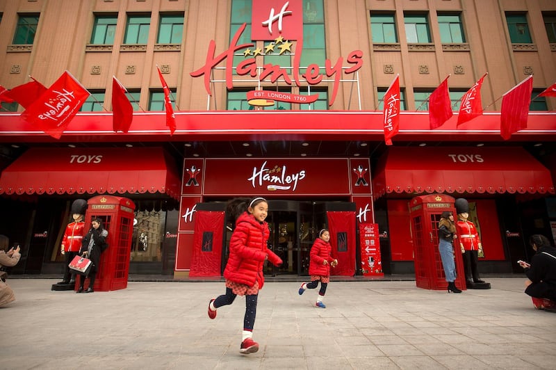 Girls run along the sidewalk in front of Hamleys toy store during its grand opening in Beijing, Saturday, Dec. 23, 2017. The British toy retailer opened its largest store in the world on Saturday just ahead of the Christmas holiday, which at five floors and 115,000 square feet (10,700 square meters) is twice the size of the chain's flagship London location and one of the largest toy stores in the world. (AP Photo/Mark Schiefelbein)