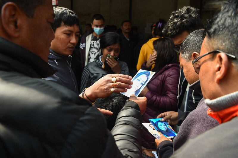 Family members of a plane crash victim hold pictures of their loved ones outside a morgue at the Teaching Hospital in Kathmandu on March 13, 2018, a day after the deadly crash of a US-Bangla Airlines plane at the international airport. Prakash Mathema / AFP