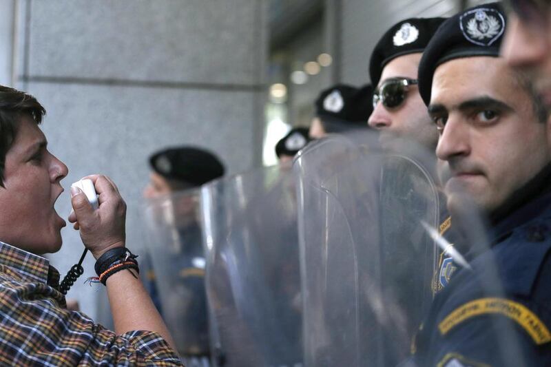 A cleaner chants slogans through a loudspeaker in front of  riot police men that secure the entrance of the Greek finance ministry, in Athens. Greek finance minister Yannis Stournaras held new negotiations with representatives of the debt-mired country’s bailout creditors on demanded reforms, following six months of fruitless on-and-off talks. Petros Giannakouris / AP Photo