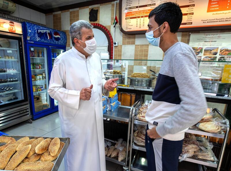 Abu Dhabi, United Arab Emirates, January 10, 2021.  
Saeed Yousef Mardi of Al Yousuf Sweets and Bakeries has a chat with some customers before giving them bread.
Victor Besa/The National
Section:  NA
Reporter:  Shireena Al Nowais