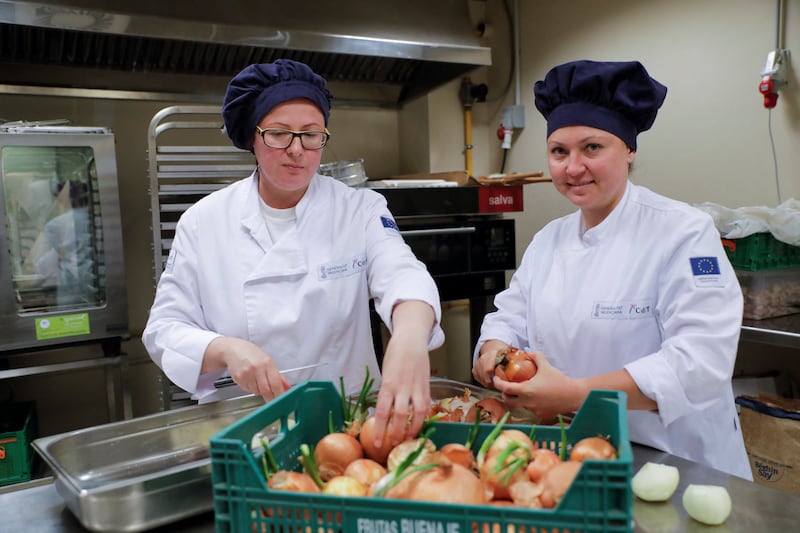 Larysa Biachenko, 40, who does not know if her house in Chernihiv is still standing, and Svitlana Lykhonos, 43, who was the owner of a hotel restaurant in Frankiusk, peel onions at a special cooking course run by the regional government to offer them a job opportunity, in Alicante, Spain. Reuters