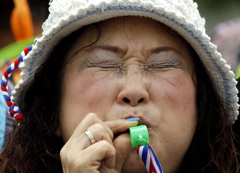 A Thai anti-government protester blows a whistle on February 20, 2014, during a rally to shut down the Shinawatra Tower III office building in Bangkok, Thailand. Thousands of protesters massed outside the building, which houses firms partly owned by the family of caretaker prime minister Yingluck Shinawatra. They berated the Shinawatras for corruption and deception, but stopped short of invading the building in a renewed bid to force her resignation. Rungroj Yongrit / EPA