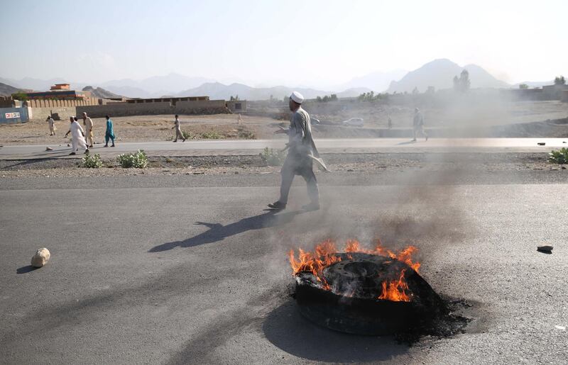 epa07012377 People walk near a burning tire after a suicide bomb attack in Mohmand Dara district of Nangarhar province, Afghanistan, 11 September 2018. At least 30 people were killed and 57 wounded on 11 September, in Mohmand Dara district, the eastern Afghan province of Nangarhar in a suicide attack on protesters who were calling for the dismissal of a police commander.  EPA/GHULAMULLAH HABIBI