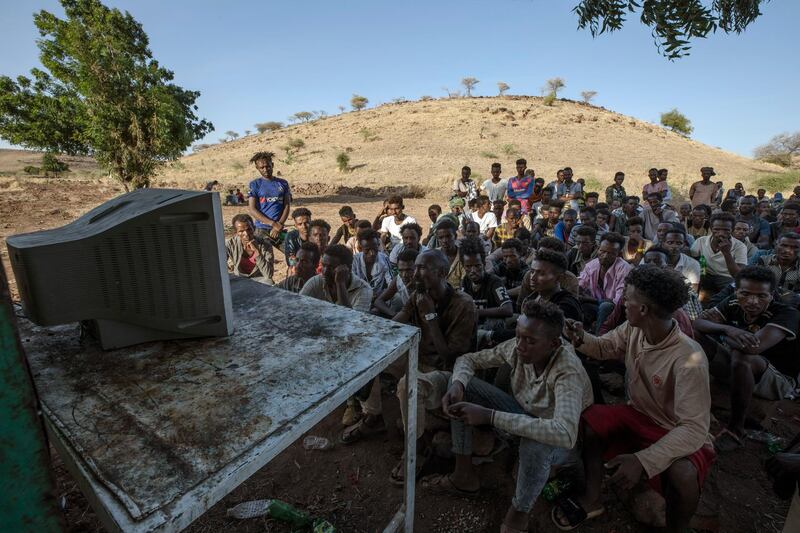 Men who fled the conflict in Ethiopia's Tigray region watch the news on a television, at Umm Rakouba refugee camp in Qadarif, eastern Sudan. AP